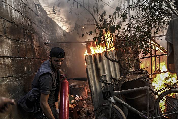 Gizon bat bonba batek eragindako sutea itzali nahian, Duman (Siria). MOHAMMED BADRA / EFE