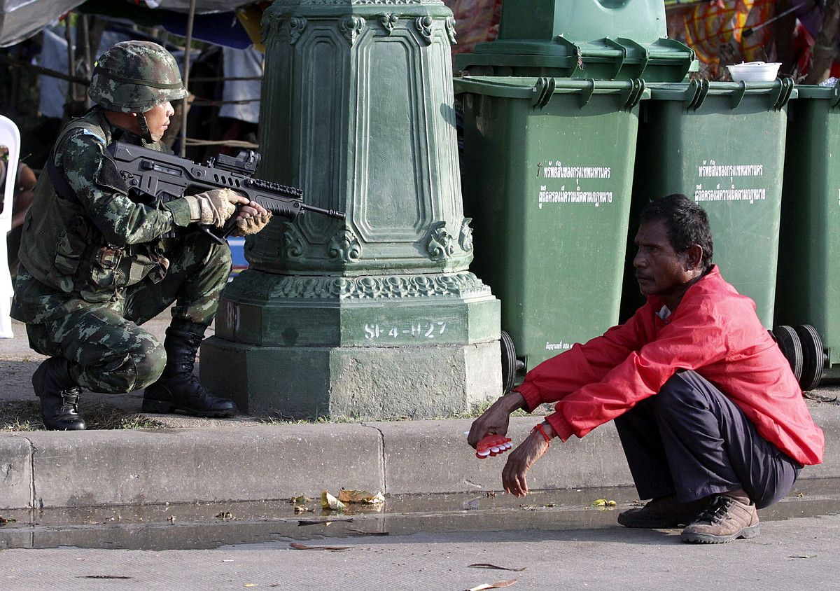 Soldadu bat, posizioa hartuta, Bangkok hiriburuan, militarrek atxikitako elastiko gorrietako manifestari baten ondoan. EFE.