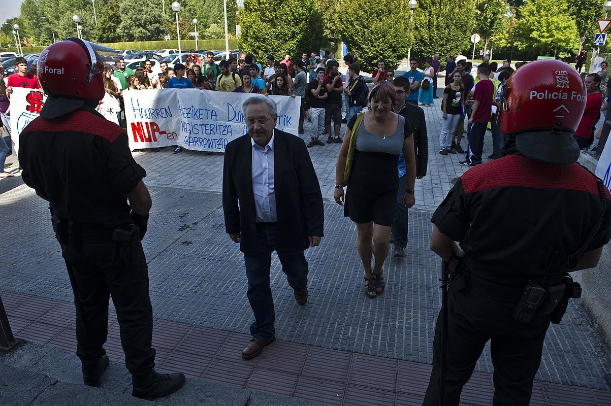 Nafarroako parlamentariak, NUPeko ikasturte hasierako ekitaldira sartzen, poliziek babestuta. Alboan, ikasleak, protestan. LANDER FERNANDEZ ARROIABE / ARP.