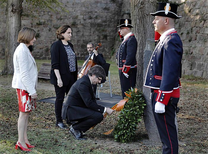 Carles Puigdemont, Carme Forcadell eta Ada Colau ondoan dituela, Lluis Comanysen hilobian lore sorta eskaintzen. ANDREU DALMAU, EFE