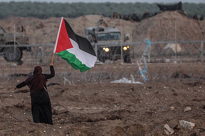 Emakume bat Palestinako bandera bat eskuetan duela, Israelgo armadako ibilgailu baten aurrean. MOHAMMED SABER, EFE