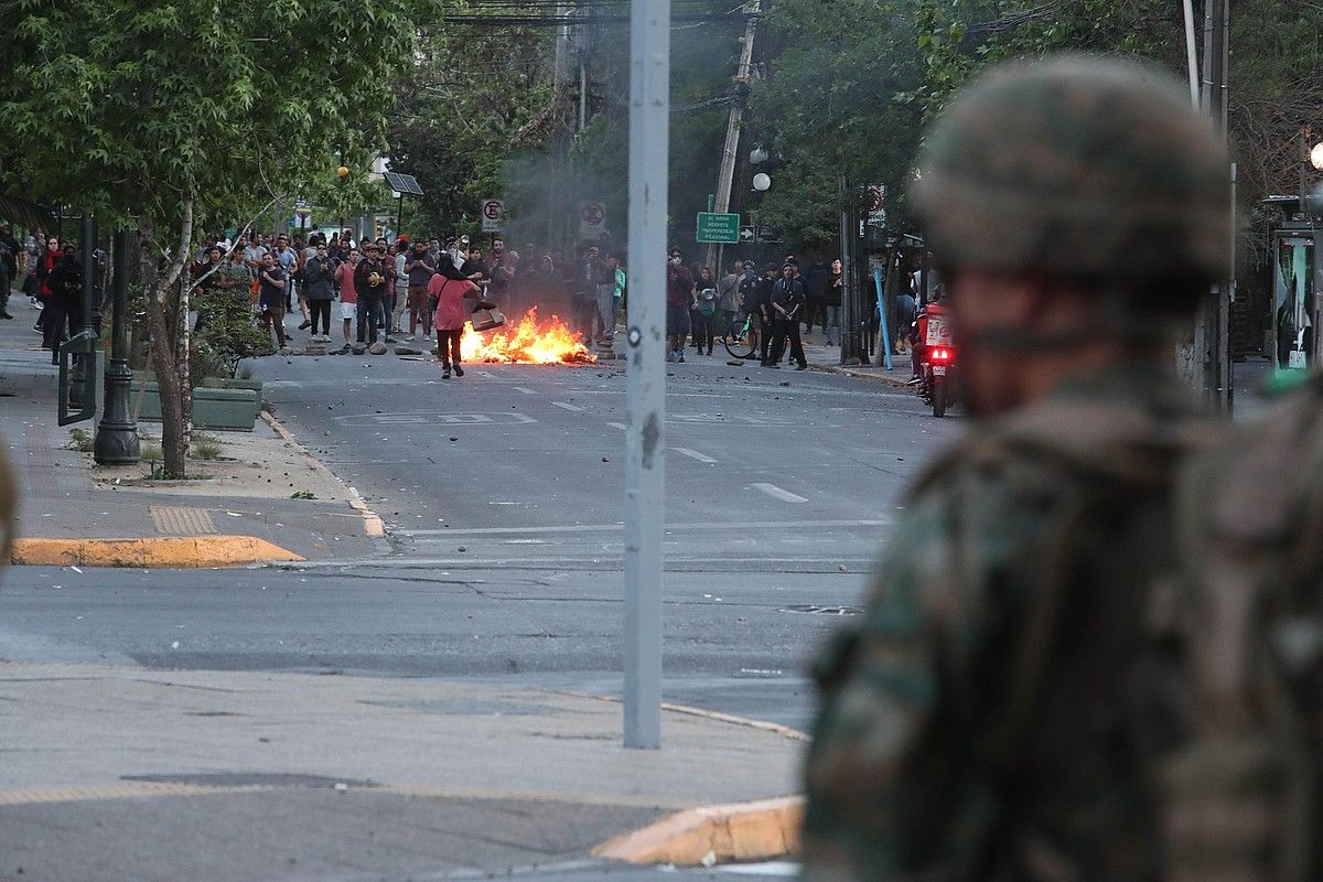 Manifestariak barrikada bat pizten militarren aurrean Santiagon, herenegun. ALBERTO PEÑA / EFE.