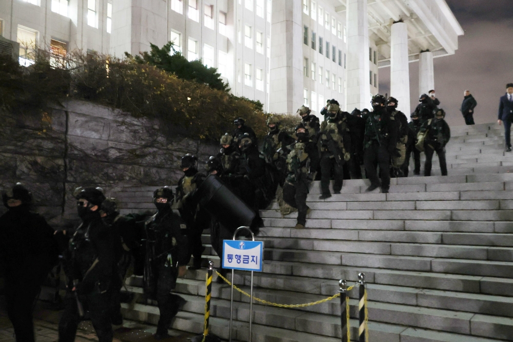 Militarrak parlamentuaren eraikinetik ateratzen, diputatuek legea indargabetzearen alde bozkatu ostean. YONHAP / EFE