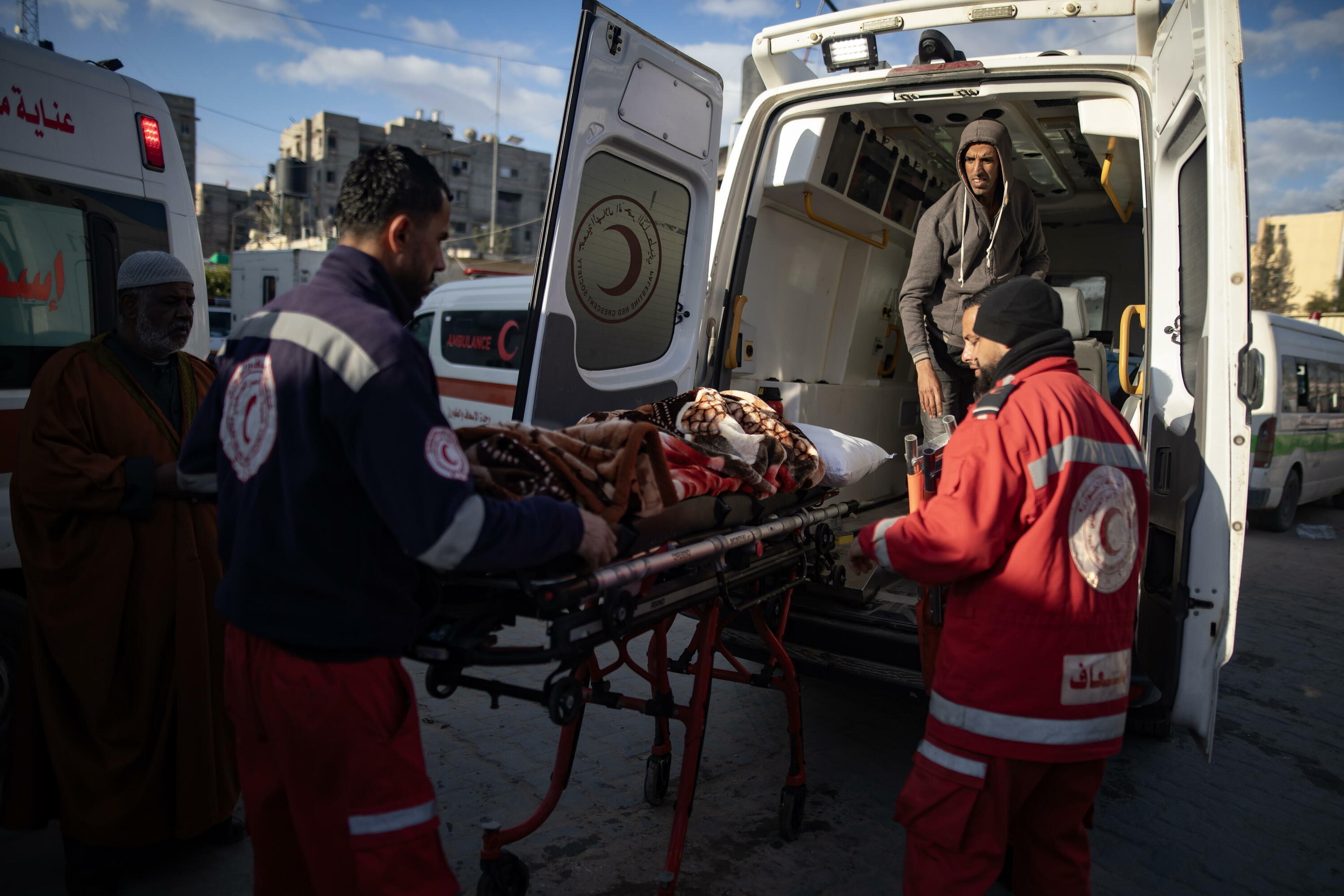 Palestinako Ilargi Gorriko langileak zauritutako adingabe bat anbulantziara sartzen, Rafahko pasabidera eramateko, gaur, Khan Yunisen. HAITHAM IMAD / EFE