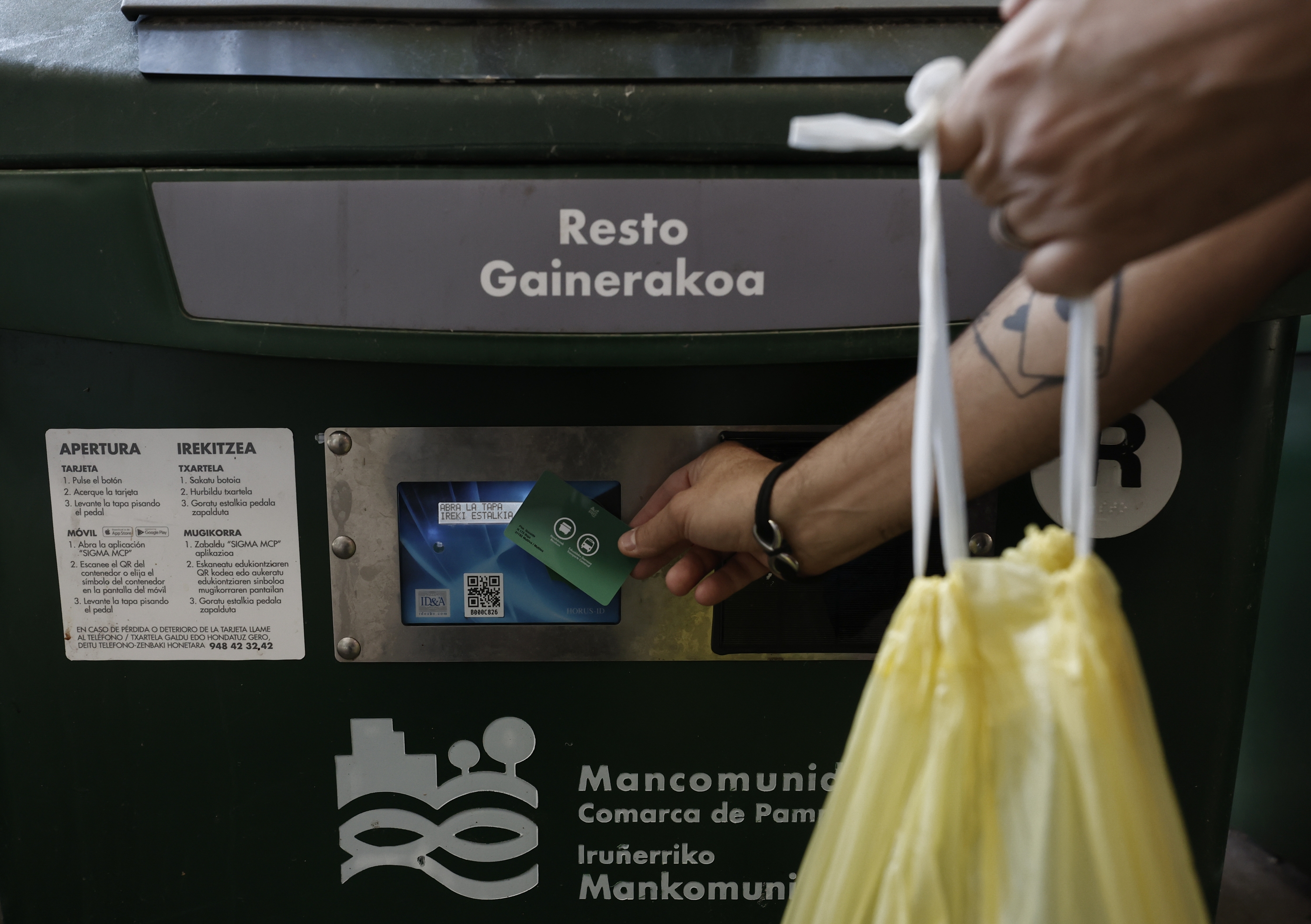 Iruñeko bizilagun bat hondakinak botatzen, sistema elektronikoz irekitzen den edukiontzi batean. JESUS DIGES / EFE