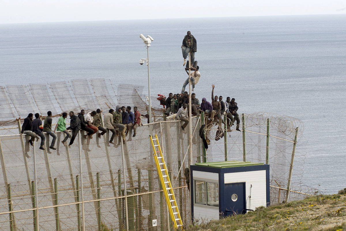 Migratzaileak Melillako hesia igarotzen saiatzen. PACO F. GUERRERO / EFE