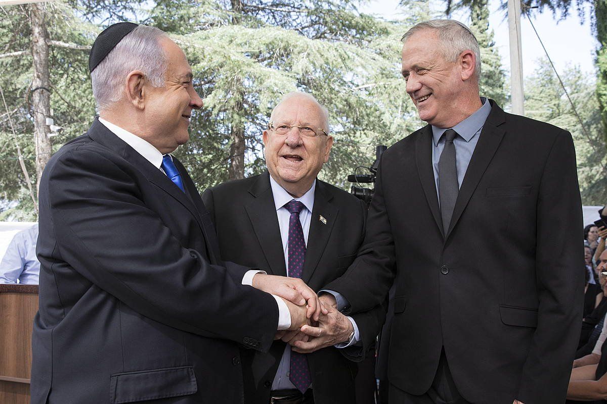 Benjamin Netanyahu eta Bnny Gantz elkarri eskua ematen, Reuven Rivlin presidentea begira dutela. ABIR SULTAN, EFE